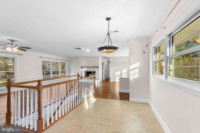 hallway with visible vents, a healthy amount of sunlight, and baseboards