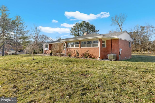 exterior space with brick siding, cooling unit, a chimney, and a front yard