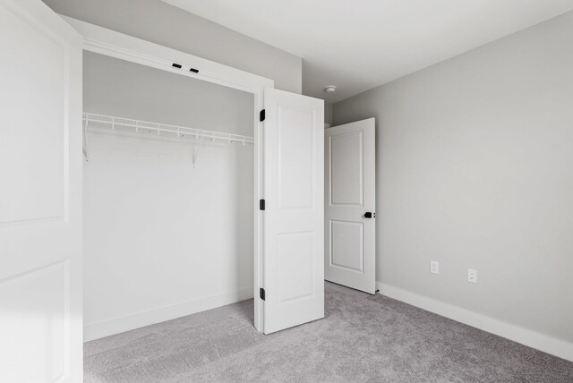 unfurnished bedroom featuring a closet and light carpet