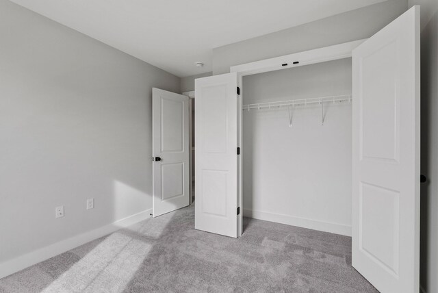 unfurnished bedroom with light colored carpet and a closet