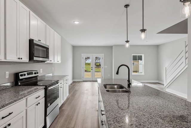 kitchen featuring pendant lighting, white cabinetry, sink, dark stone countertops, and stainless steel appliances