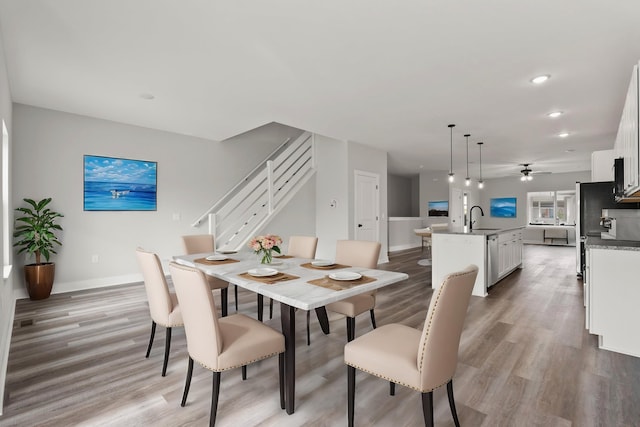 dining room featuring sink, wood-type flooring, and ceiling fan