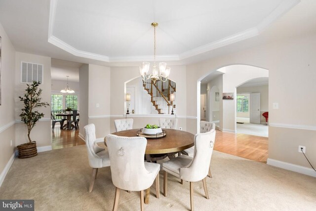 carpeted dining area with a raised ceiling and an inviting chandelier