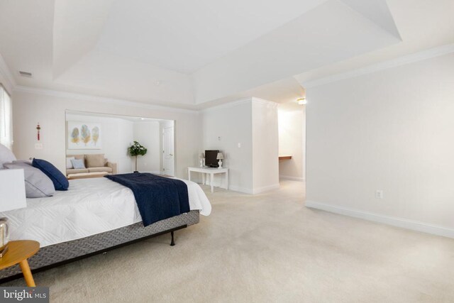 carpeted bedroom with ornamental molding and a tray ceiling