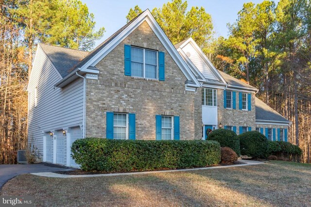 view of front of house featuring cooling unit, a garage, and a front yard