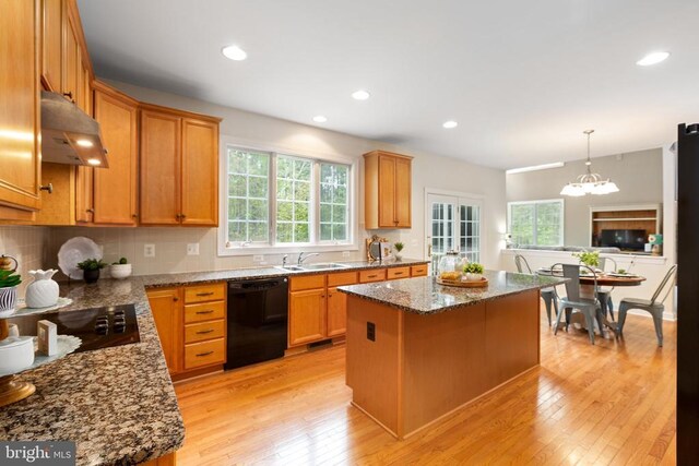 kitchen featuring light stone counters, decorative light fixtures, black appliances, and a kitchen island