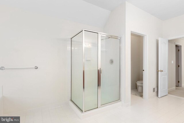 bathroom featuring toilet and a shower with shower door