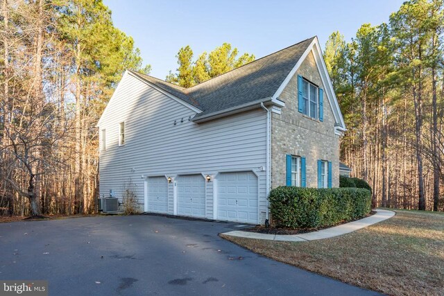 view of side of home featuring cooling unit and a garage