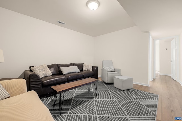 living area featuring baseboards, visible vents, and wood finished floors