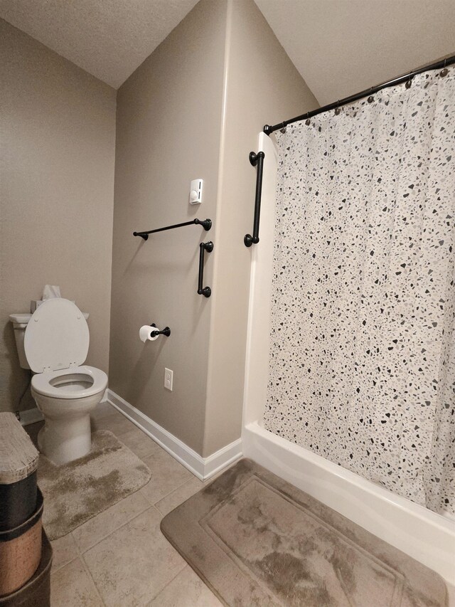 bathroom featuring a shower stall, toilet, tile patterned floors, and baseboards