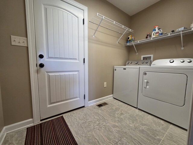 washroom featuring baseboards, visible vents, separate washer and dryer, and laundry area
