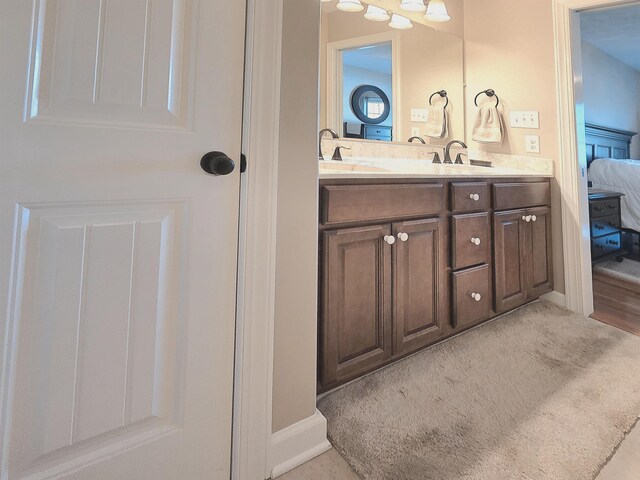 full bath featuring baseboards, a sink, double vanity, and connected bathroom