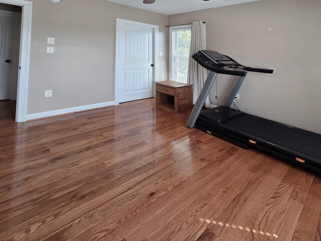 exercise area featuring baseboards, wood finished floors, and ceiling fan