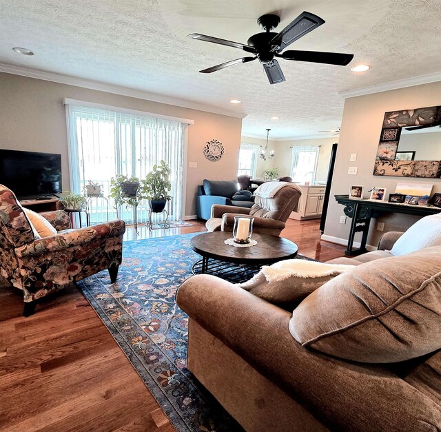 living area featuring a ceiling fan, wood finished floors, a textured ceiling, ornamental molding, and recessed lighting