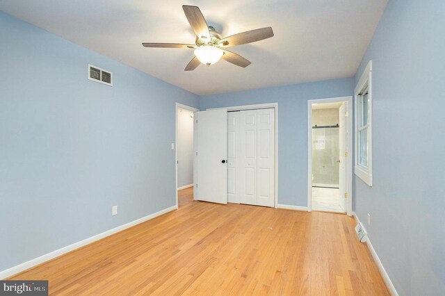 unfurnished bedroom with a closet, ceiling fan, ensuite bath, and light hardwood / wood-style flooring