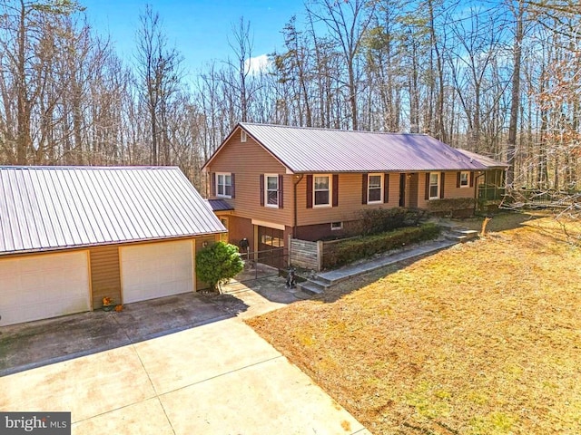 view of front of home with driveway, an attached garage, a front lawn, and metal roof