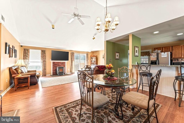 dining area featuring lofted ceiling, light wood finished floors, visible vents, and a ceiling fan