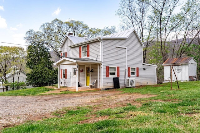 traditional-style home featuring a front lawn, a storage shed, an outbuilding, a porch, and ac unit
