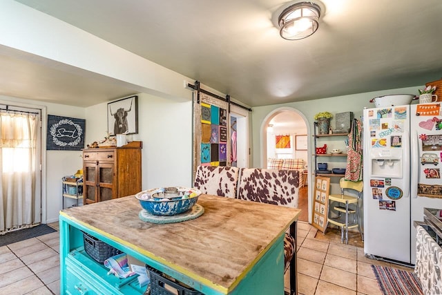 dining room with a barn door, arched walkways, and light tile patterned flooring