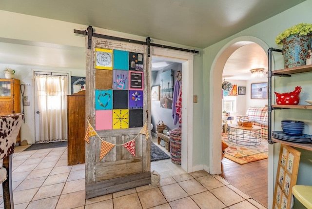 hallway with tile patterned flooring, arched walkways, and a barn door