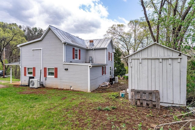 rear view of property featuring a storage shed, metal roof, ac unit, an outdoor structure, and a yard