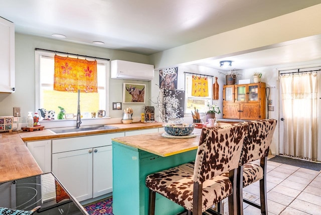 kitchen with an AC wall unit, a sink, a center island, black electric stovetop, and a breakfast bar area