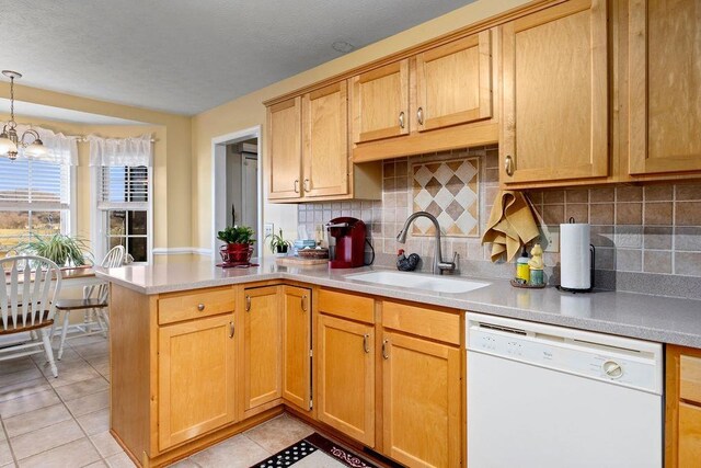 kitchen featuring sink, white dishwasher, light tile patterned flooring, decorative light fixtures, and kitchen peninsula