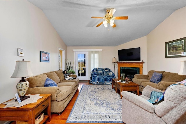 living room with ceiling fan, wood-type flooring, vaulted ceiling, and a high end fireplace