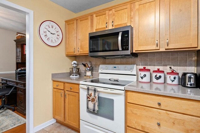 kitchen featuring backsplash, light tile patterned floors, and electric range