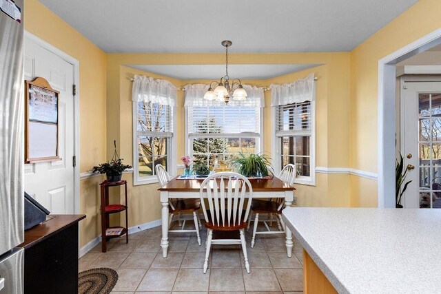 dining space with light tile patterned floors and an inviting chandelier