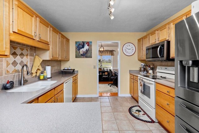 kitchen featuring sink, tasteful backsplash, a textured ceiling, light tile patterned floors, and appliances with stainless steel finishes