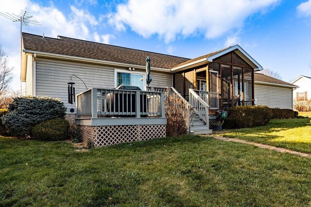 back of property featuring a wooden deck, a sunroom, and a lawn