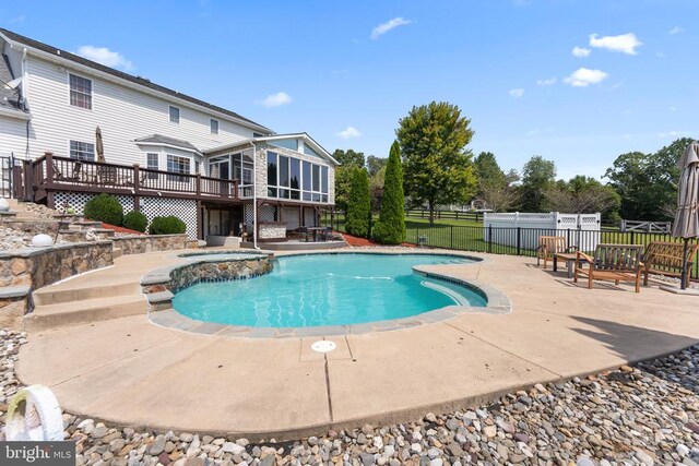 view of pool with an in ground hot tub, a deck, a patio area, and a sunroom