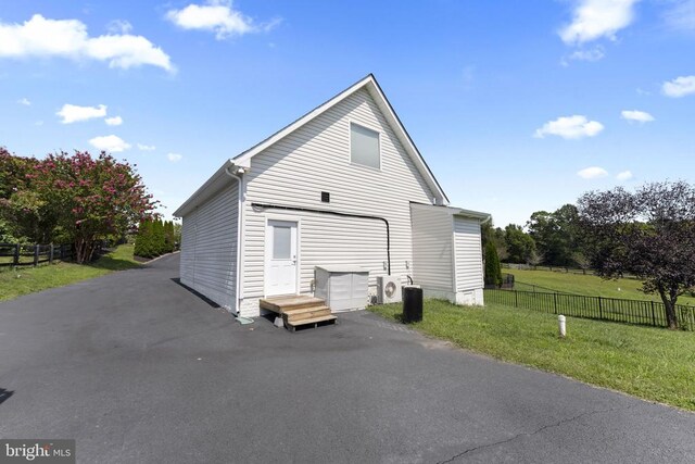 back of property with ac unit and a lawn