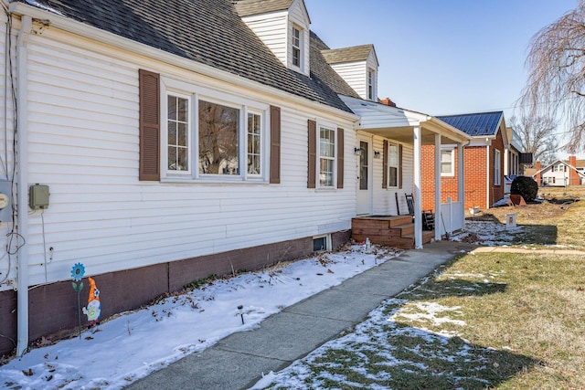 view of snow covered exterior with roof with shingles