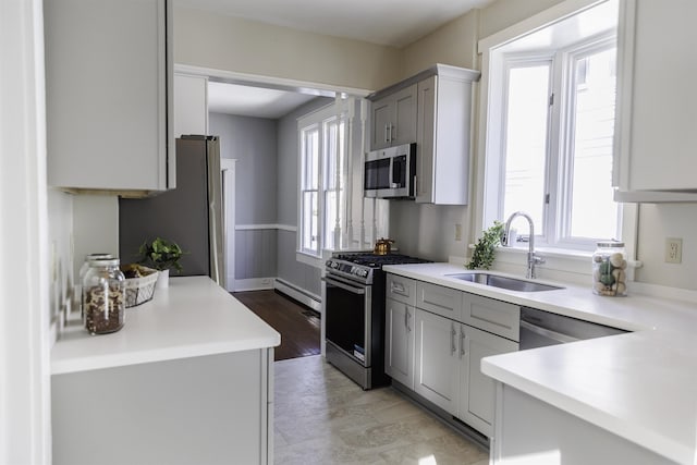 kitchen with plenty of natural light, stainless steel appliances, sink, and gray cabinetry