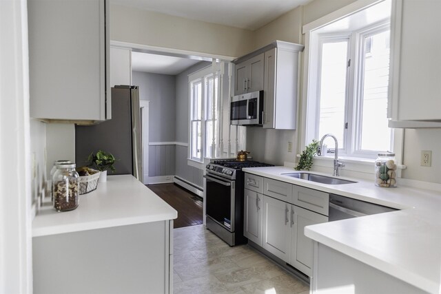 kitchen with plenty of natural light, stainless steel appliances, sink, and gray cabinetry