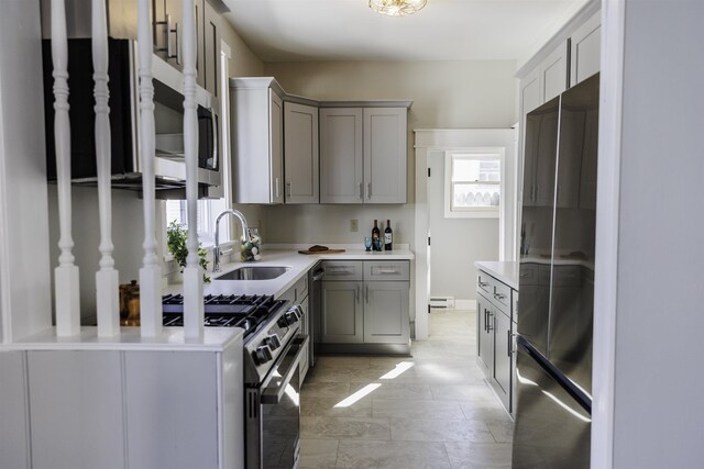 kitchen featuring stainless steel appliances, gray cabinets, sink, and a baseboard heating unit