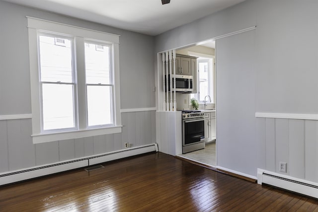 kitchen featuring a baseboard radiator, stainless steel appliances, dark hardwood / wood-style flooring, and a wealth of natural light