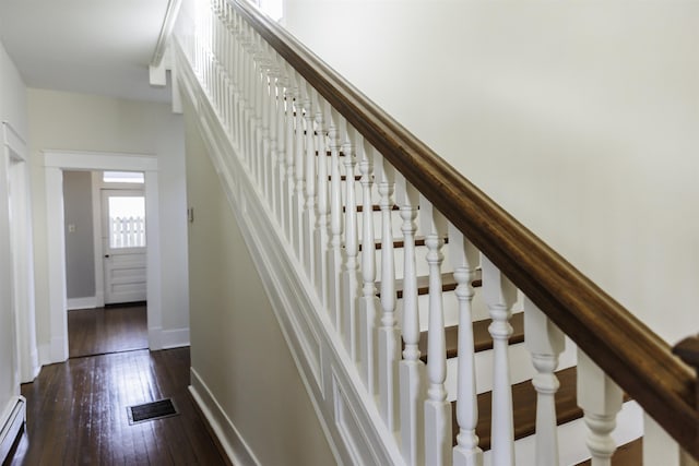 staircase featuring a baseboard heating unit and wood-type flooring