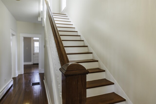 staircase featuring wood-type flooring and baseboard heating