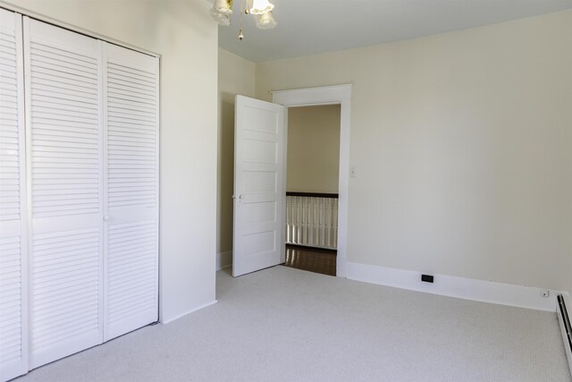 unfurnished bedroom featuring a baseboard radiator, carpet, and a closet