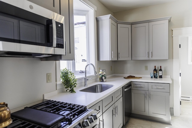 kitchen featuring gray cabinets, appliances with stainless steel finishes, sink, and baseboard heating