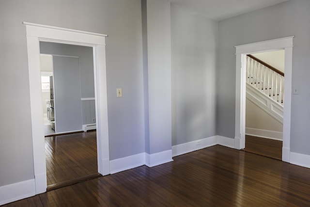 unfurnished room featuring a baseboard radiator and dark hardwood / wood-style floors