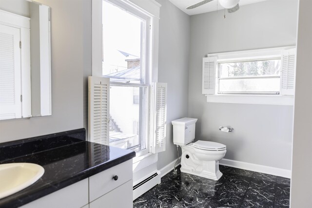 bathroom with vanity, plenty of natural light, a baseboard heating unit, and toilet