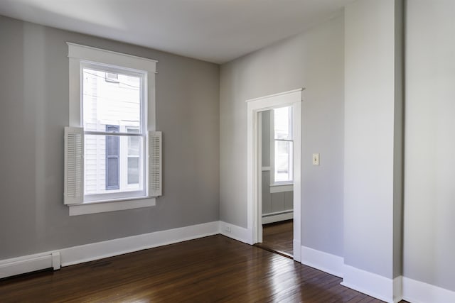 spare room with a baseboard radiator and dark hardwood / wood-style floors