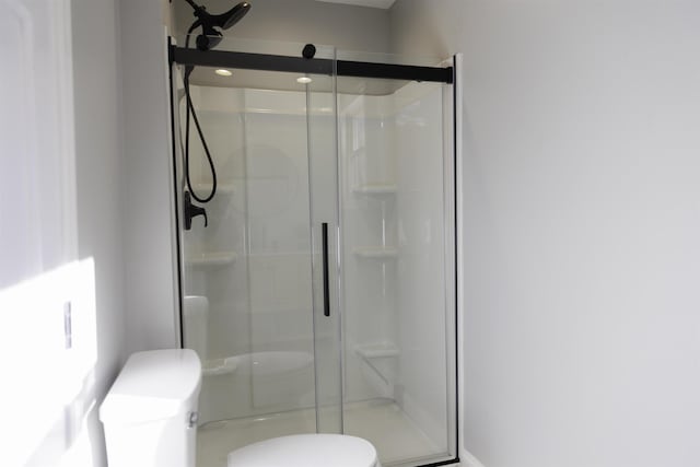 bathroom with a shower with shower door and toilet