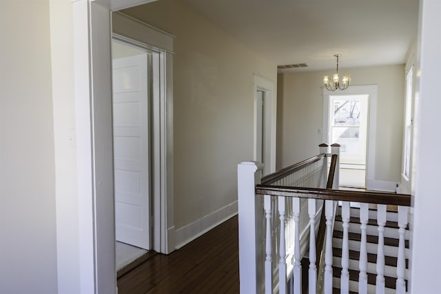 hall with dark hardwood / wood-style floors and a notable chandelier