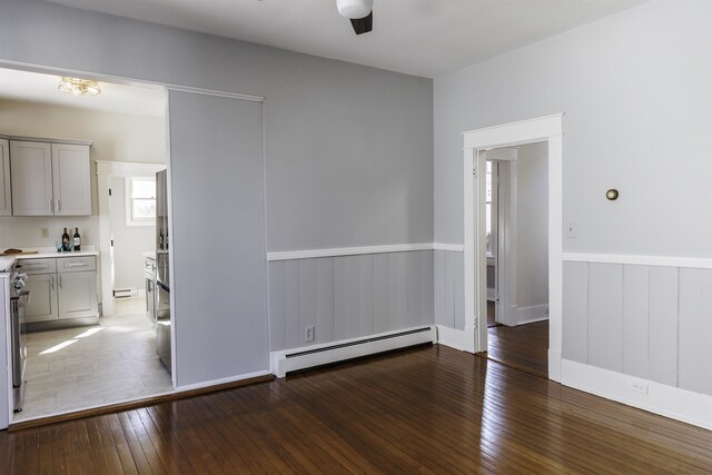 empty room featuring dark hardwood / wood-style floors, ceiling fan, and baseboard heating