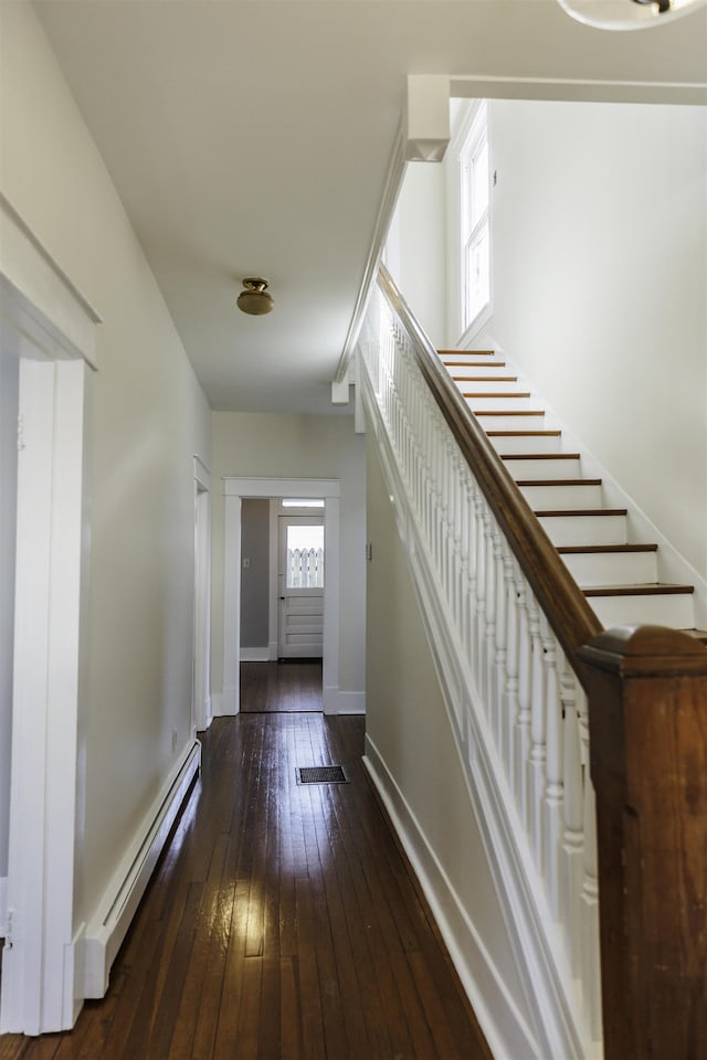 corridor featuring plenty of natural light, a baseboard heating unit, and dark hardwood / wood-style floors